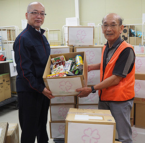 セカンドハーベスト名古屋 前川理事長（右）に食品などを手渡す当社総務部長の羽賀
