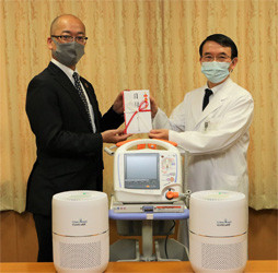 一宮市民病院の松浦院長(右)に物品を渡す当社総務部長の羽賀(左)