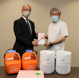 稲沢市民病院の加藤院長(右)に物品を渡す当社総務部長の羽賀(左)